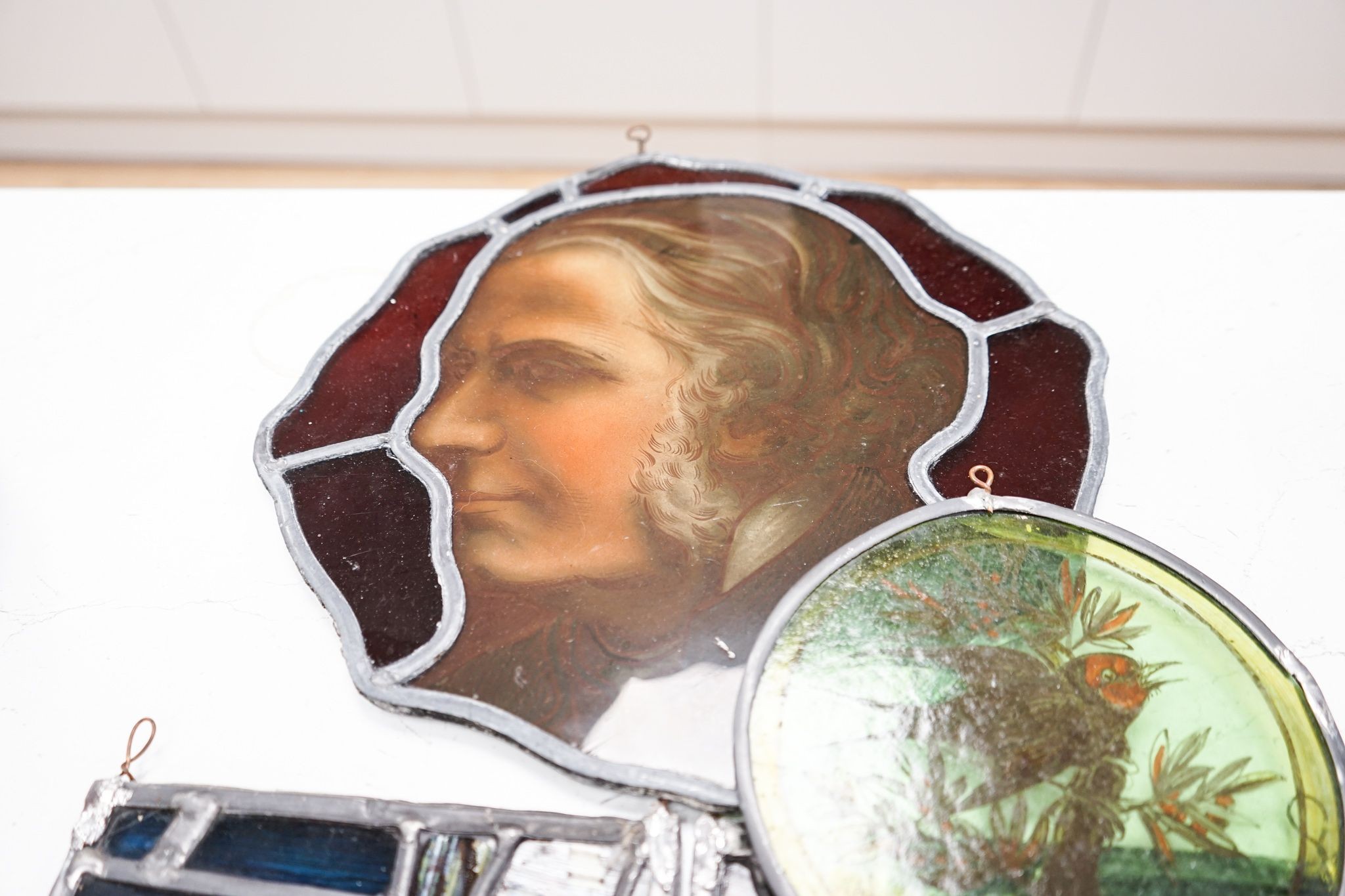 A Victorian stained glass portrait panel, two bird panels and a similar circular bird panel (4)